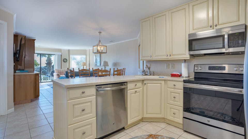 This bright, functional kitchen offers ample cabinet storage, a full suite of appliances—including stainless steel refrigerator and range—and a generous peninsula that expands your prep space.