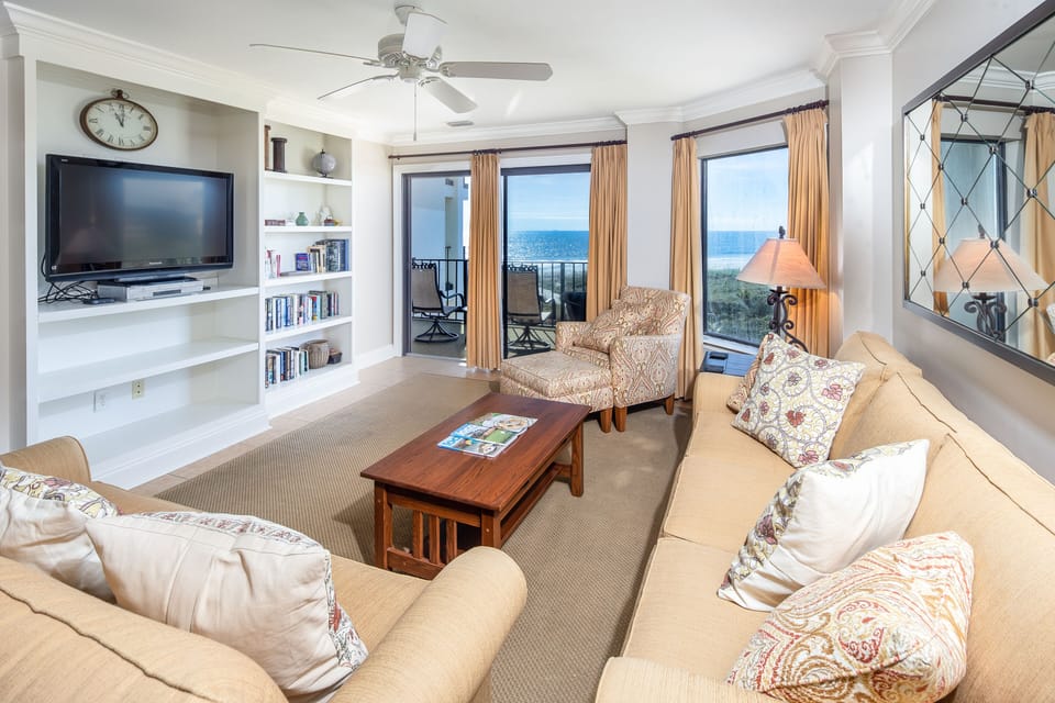 This beautifully furnished living room features sweeping ocean views framed by a large picture window and sliding glass doors that open to the private balcony.