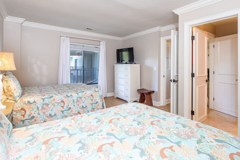 This inviting guest bedroom offers two well-appointed beds with charming coastal bedding, creating a bright and cheerful retreat for family and friends.