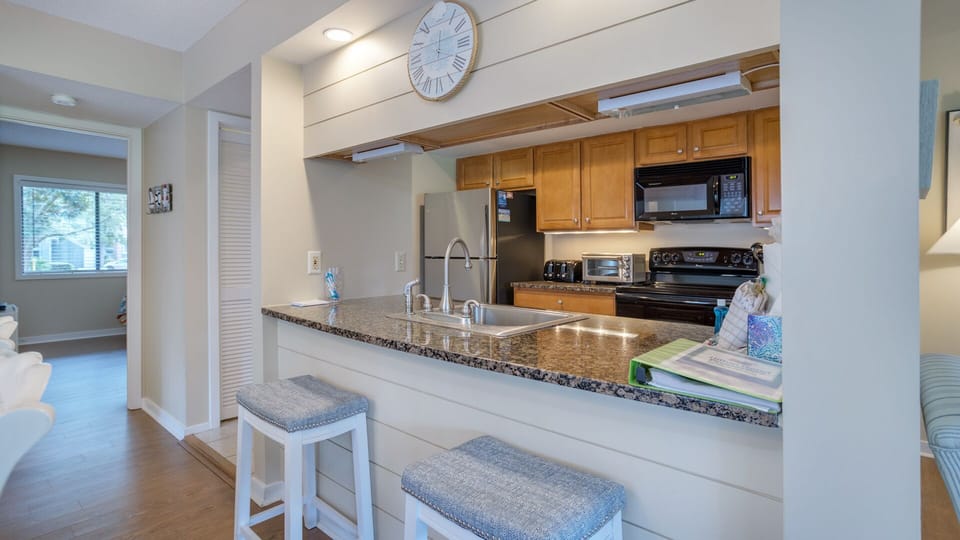 The granite breakfast bar offers casual seating and keeps the space connected to the living area, perfect for morning coffee.