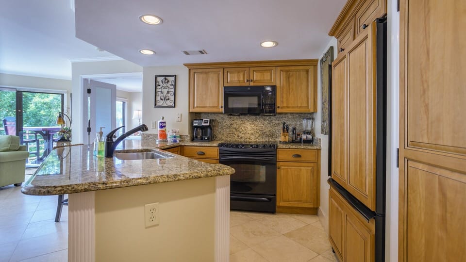 This well-equipped kitchen blends warmth and function, featuring granite countertops, custom wood cabinetry, and full-size appliances.
