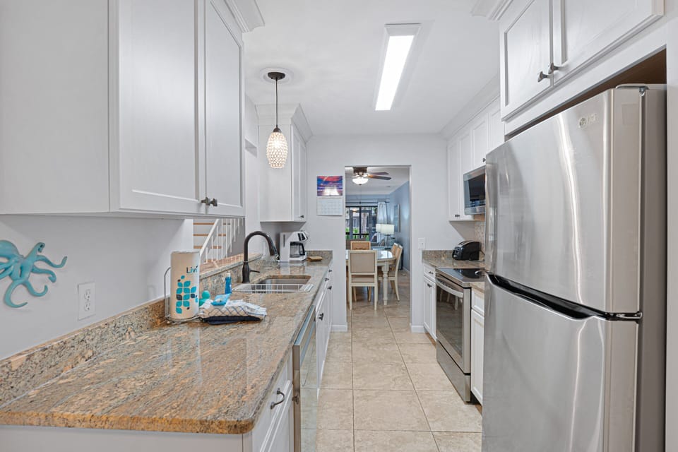 A mosaic tile backsplash adds texture and coastal charm, while ample upper and lower storage keeps everything organized.