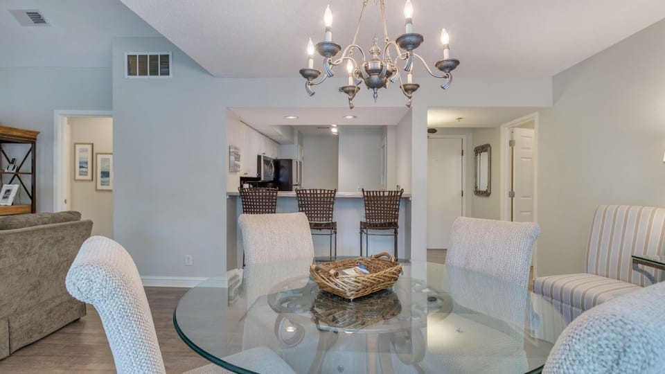 The round glass-top table comfortably seats four and flows seamlessly into the spacious living area, creating an open, inviting layout.