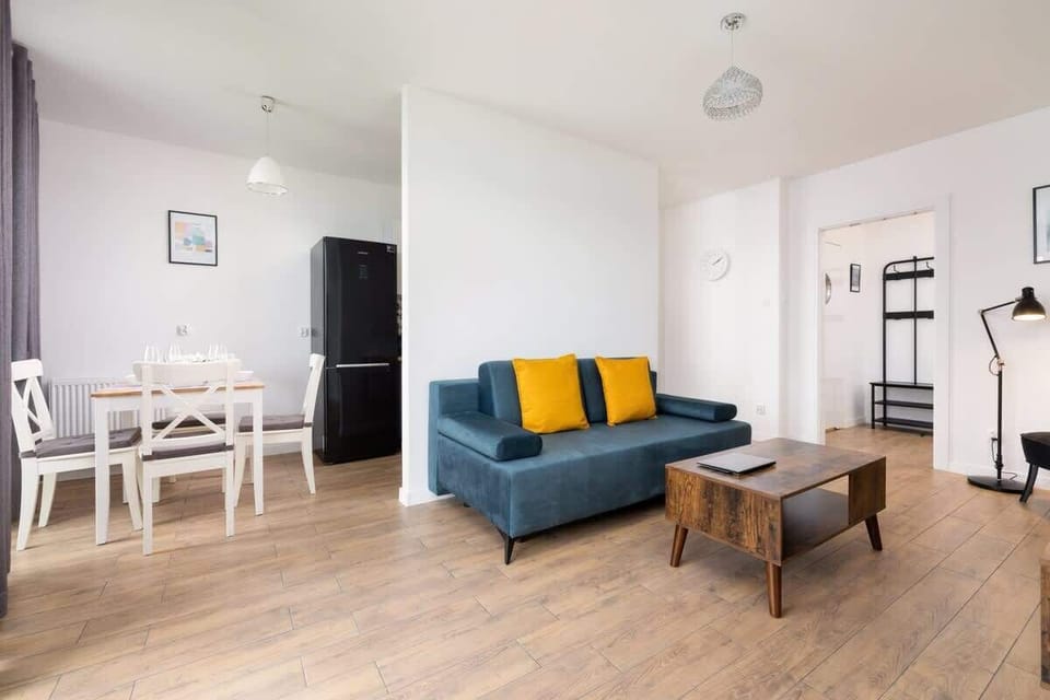 Spacious living area with blue sofa, wooden floors, and stylish decor.