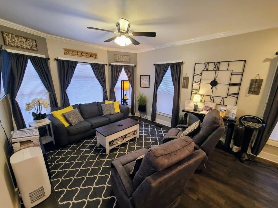 Large open living room with couch, 2 reclining gliders, air purifier and games