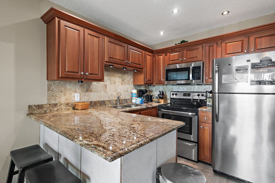 Kitchen with stainless steel appliances, Corian countertops, and breakfast bar.