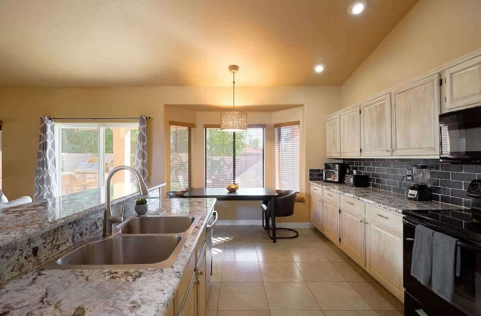 Fully equipped kitchen featuring stainless-steel appliances, kitchen island with bar seating for 3 guests, and an informal dining table with seating for 2 guests.
