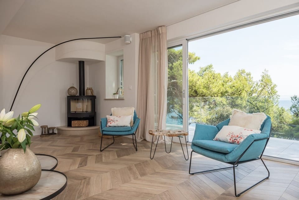 Comfortable armchairs by the fireplace of the luxury beachfront villa with private pool