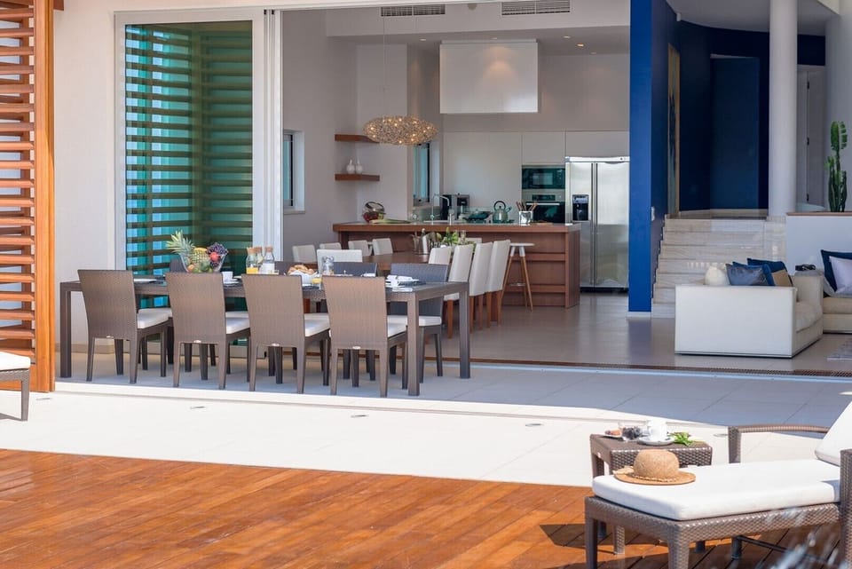 Modern interior of the living room with sofas, dining table and kitchen and terrace in a family holiday villa in Brela