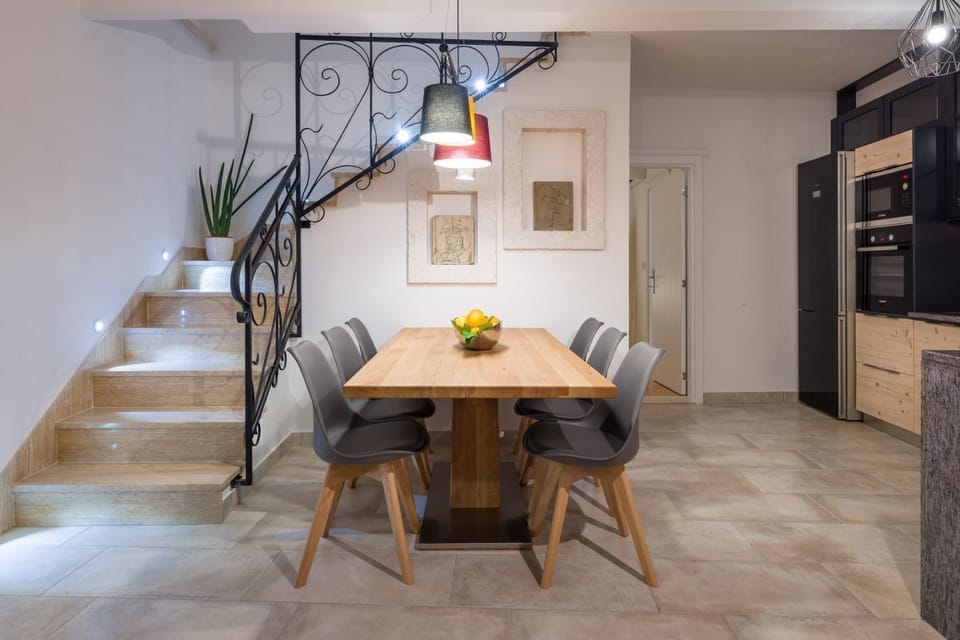 A view of the wooden dining table with chairs and the stairs leading to the first floor of the luxury villa Murvica in Murvica on the island of Brac