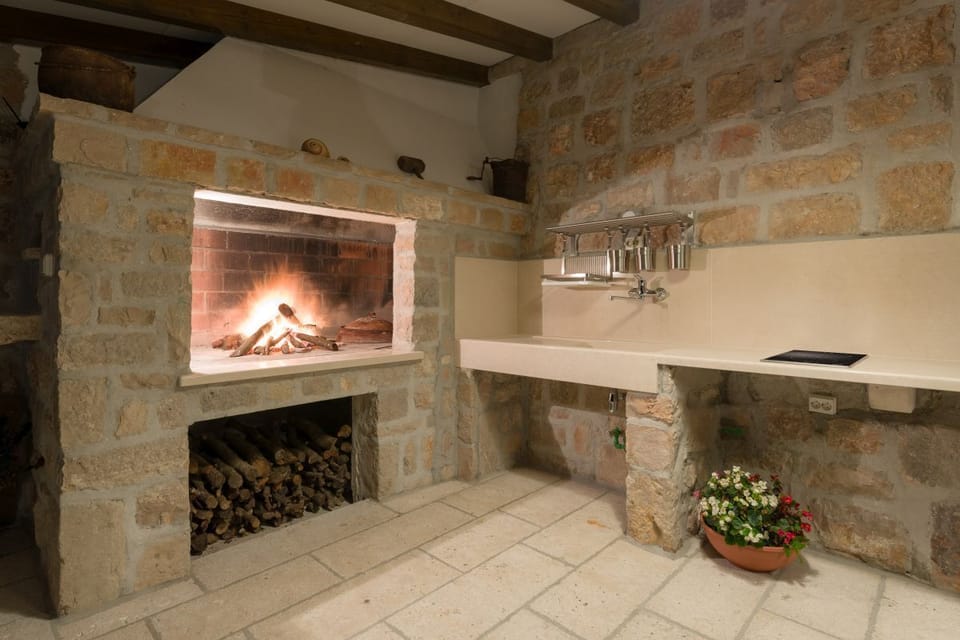 Outdoor wood-burning fireplace on the outdoor terrace of a luxury villa for vacation with friends in Murvica on the island of Brac
