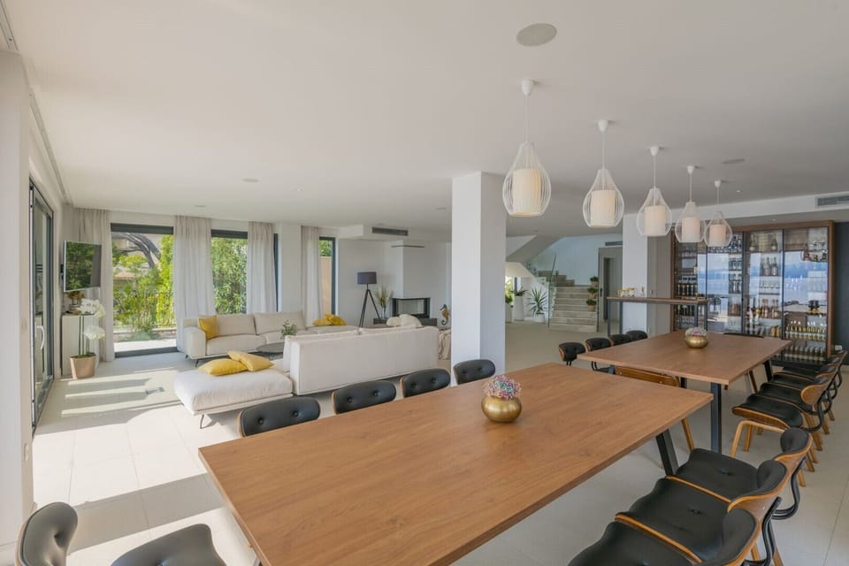 Dining table with chairs and living room with sofa and LCD TV in a luxury rental villa with private sauna in Brela
