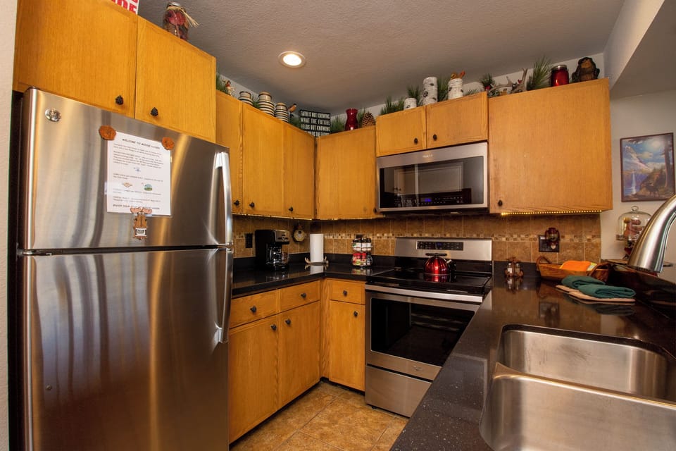 Your fully equipped kitchen awaits with stainless steel appliances, warm wood cabinets, and granite countertops—perfect for preparing memorable meals.