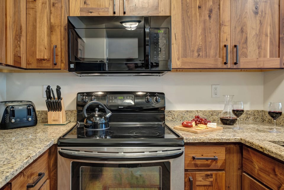 The kitchen has a stainless steel oven, black microwave and wooden cabinets.