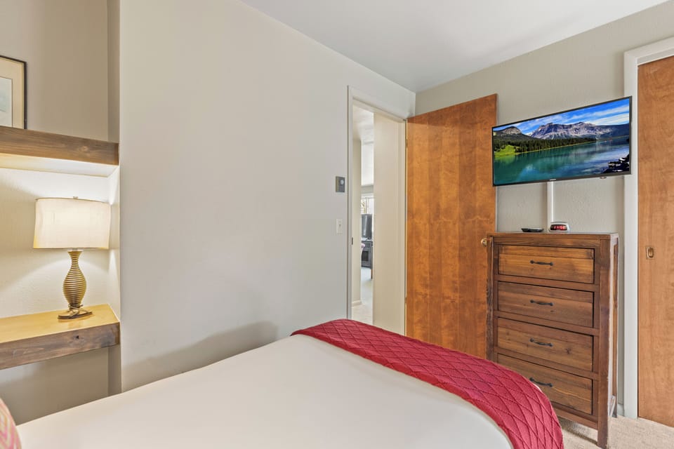The second bedroom has two twin beds and a wall mounted TV.