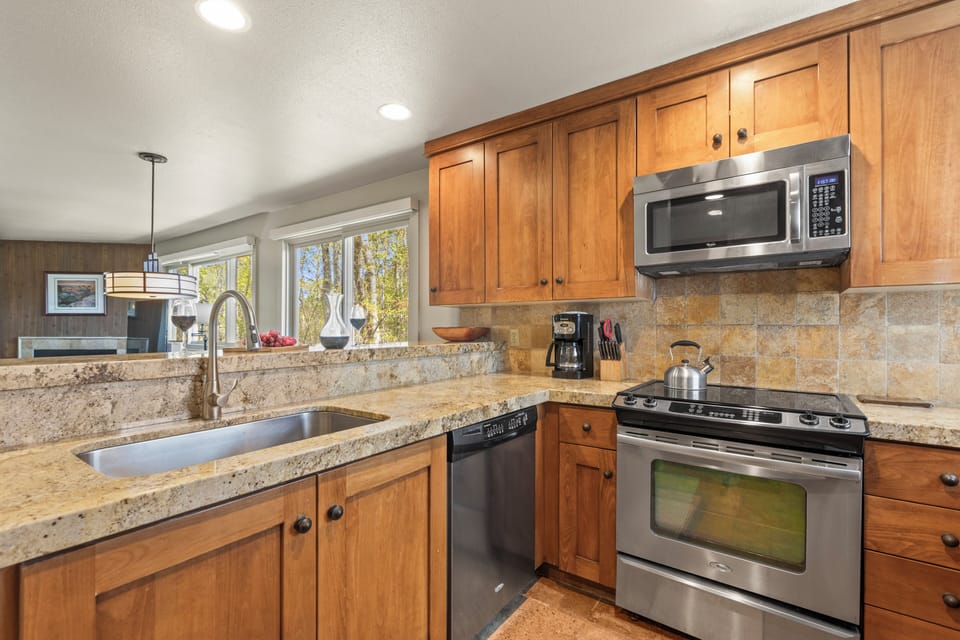 The kitchen has warm wood cabinetry, stainless steel appliances, and granite counter tops.