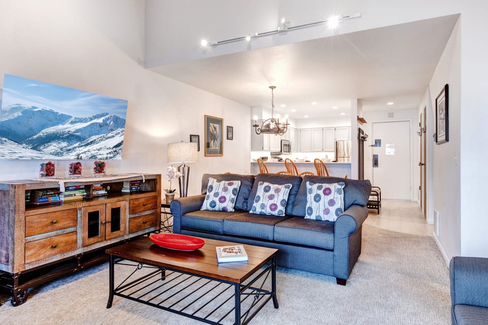 The living room offers new grey upholstered couches and wood furniture.