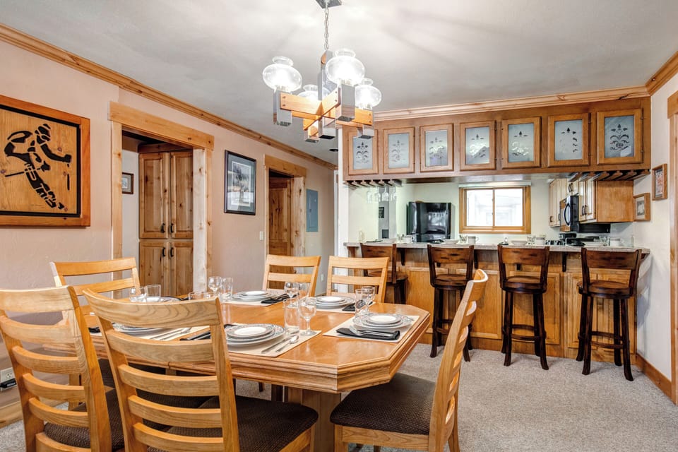 Snow Flower 43's dining room is situated next to a breakfast bar with 4 wooden stools and place settings for 4 guests.