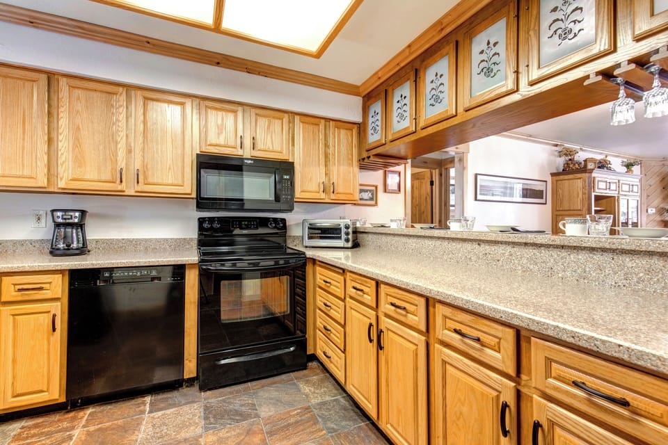 Snow Flower 43's kitchen with black appliances, oak cabinets, breakfast bar with short ceiling mounted cabinets above.