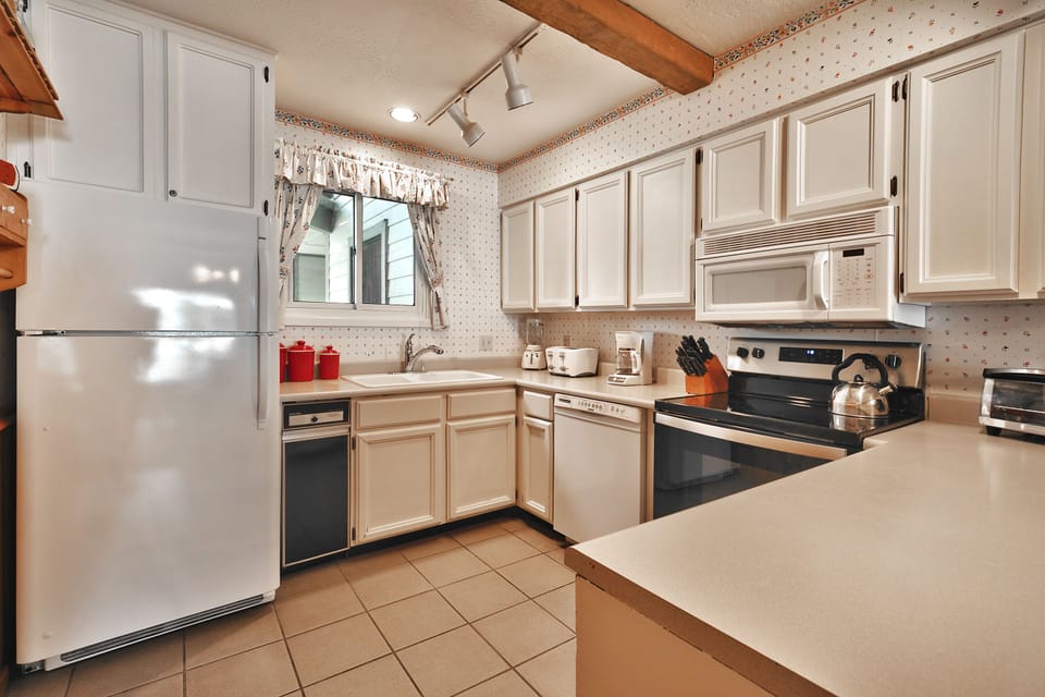 Kitchen includes tiled flooring, white countertops, cabinets and appliances.
