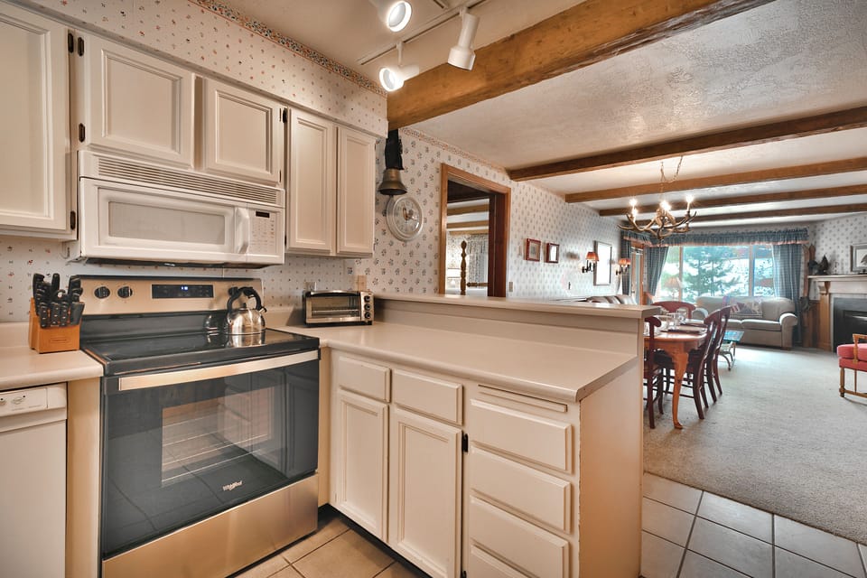 The kitchen opens into the dining area and living room with views to the slopes through the picture window