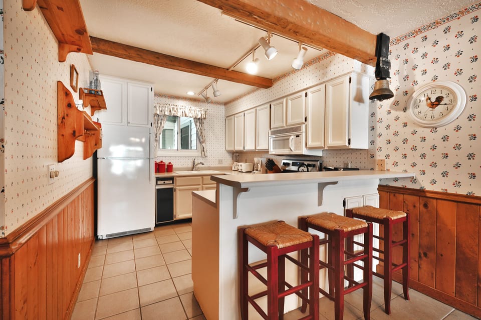 The kitchen includes a open bar area with 3 wooden bar stools