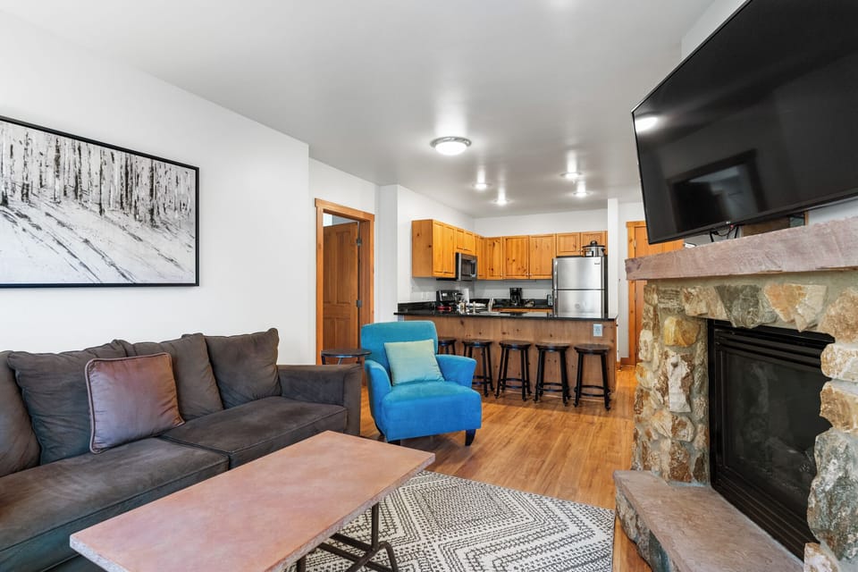 Unwind in your cozy living room with plush seating, a warming stone fireplace, and fully equipped kitchen ready for home-cooked meals.