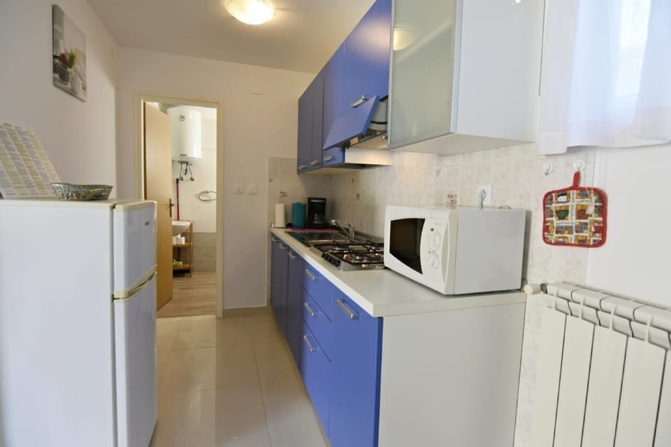 The kitchen with a stove, microwave, refrigerator with freezer area, access to the bathroom