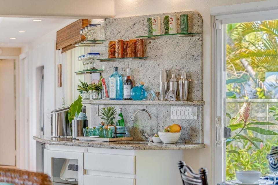 Enjoy a dedicated space for beverages featuring elegant stone backsplash and organized shelving