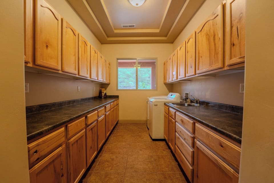 Spacious laundry room with abundant wood cabinet storage and dark countertops at Spirit of the Rock, Kanab.
