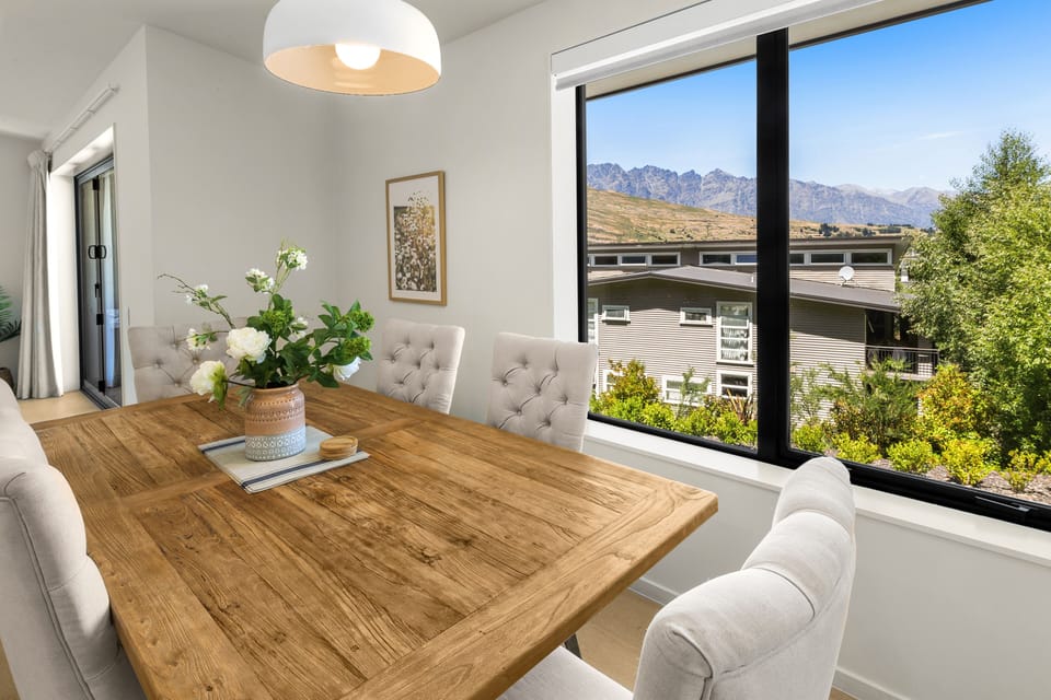 Open plan dining area with large table for six people; mountain views