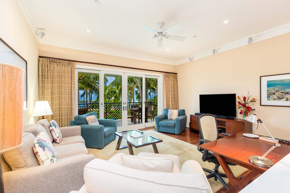 Floor-to-ceiling windows frame tropical views, creating a bright and inviting space to unwind.