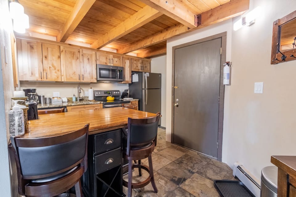Your rustic kitchen features warm wooden beams, full appliances, and a cozy breakfast bar perfect for morning coffee or casual meals together.
