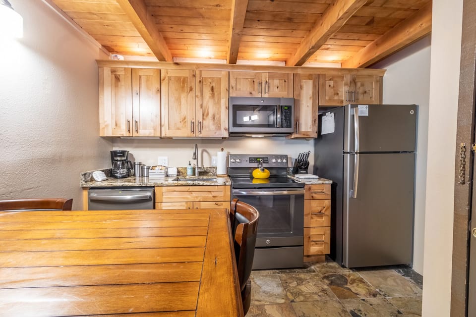 Your rustic kitchen awaits with warm wood beams overhead and modern stainless appliances ready for mountain getaway cooking.