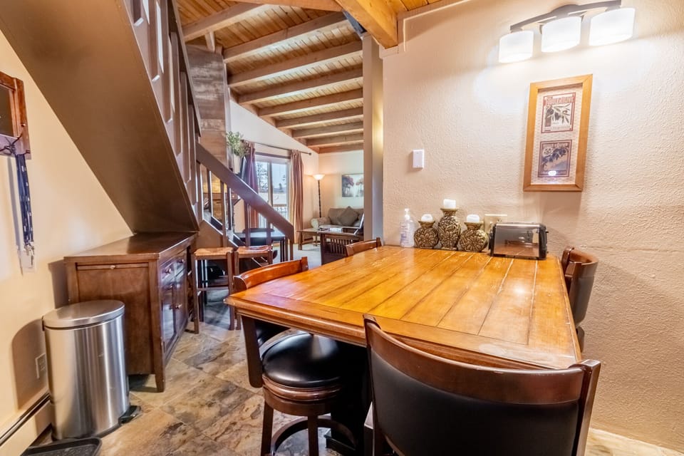 Your charming dining space features warm wood beams and a gorgeous table where memorable meals await beneath soft lighting.