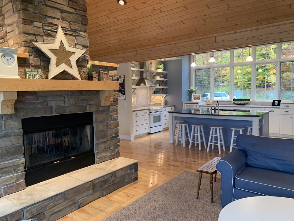 Great room with kitchen/dining/living areas separated by a two-sided fireplace 
