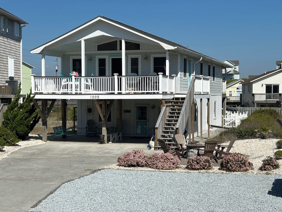 Front view with fire pit and large deck with peek-a-boo ocean views