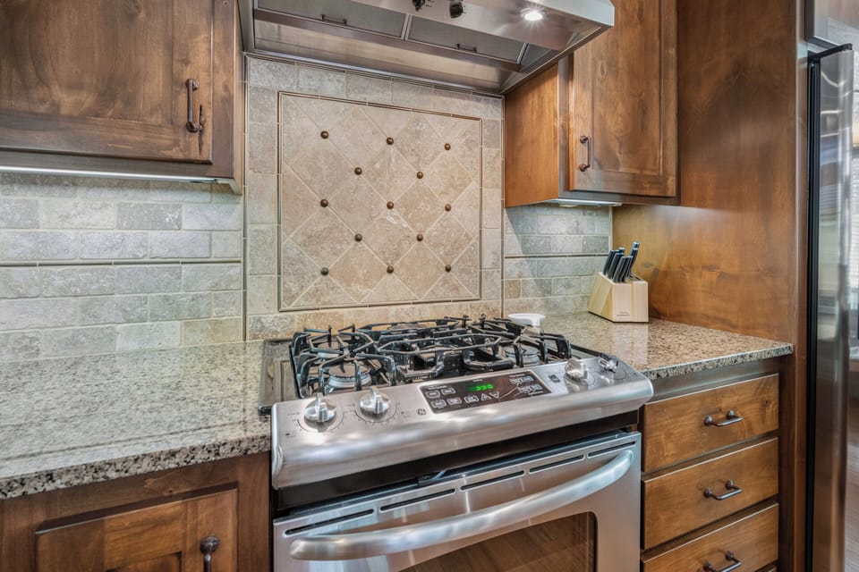 Your culinary adventures begin here, with a professional-grade stove and elegant tile backsplash that brings warmth to every meal you prepare.