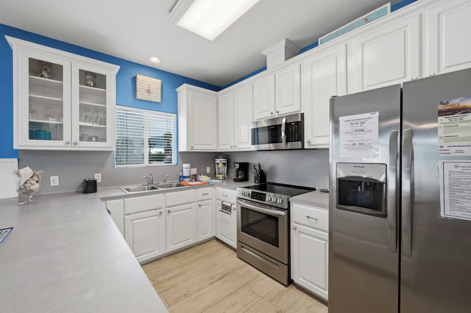 Your fully equipped kitchen features modern stainless steel appliances, bright white cabinetry, and plenty of counter space for preparing delicious meals during your stay.