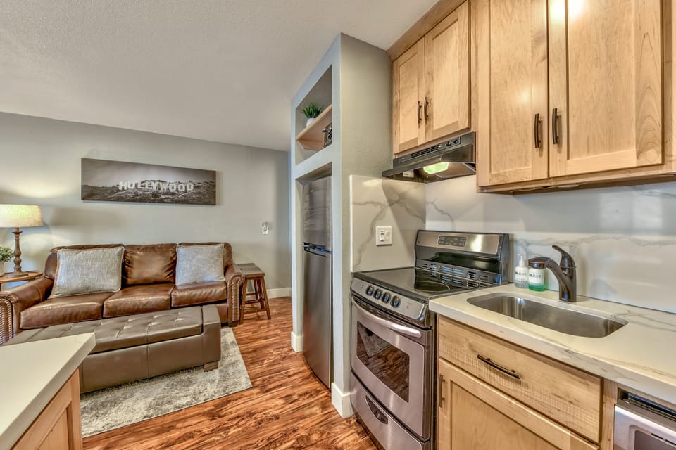 Your open-concept suite blends modern kitchen convenience with cozy living comfort, featuring warm wood cabinetry and leather seating for relaxing evenings.