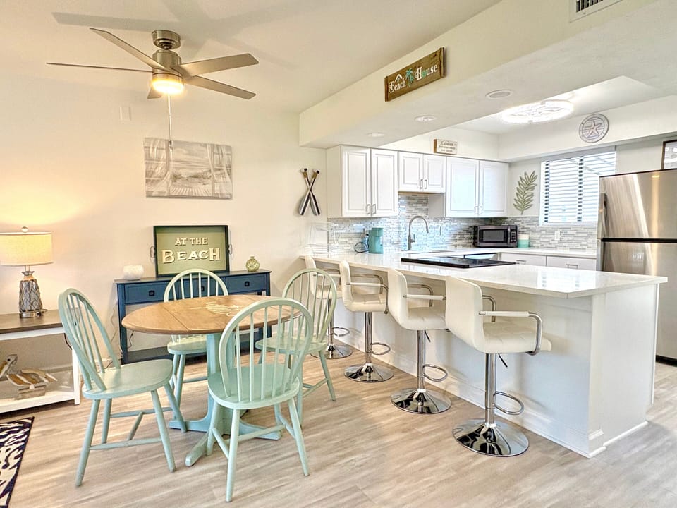 Kitchen with white cabinetry, bar stools, and coastal artwork