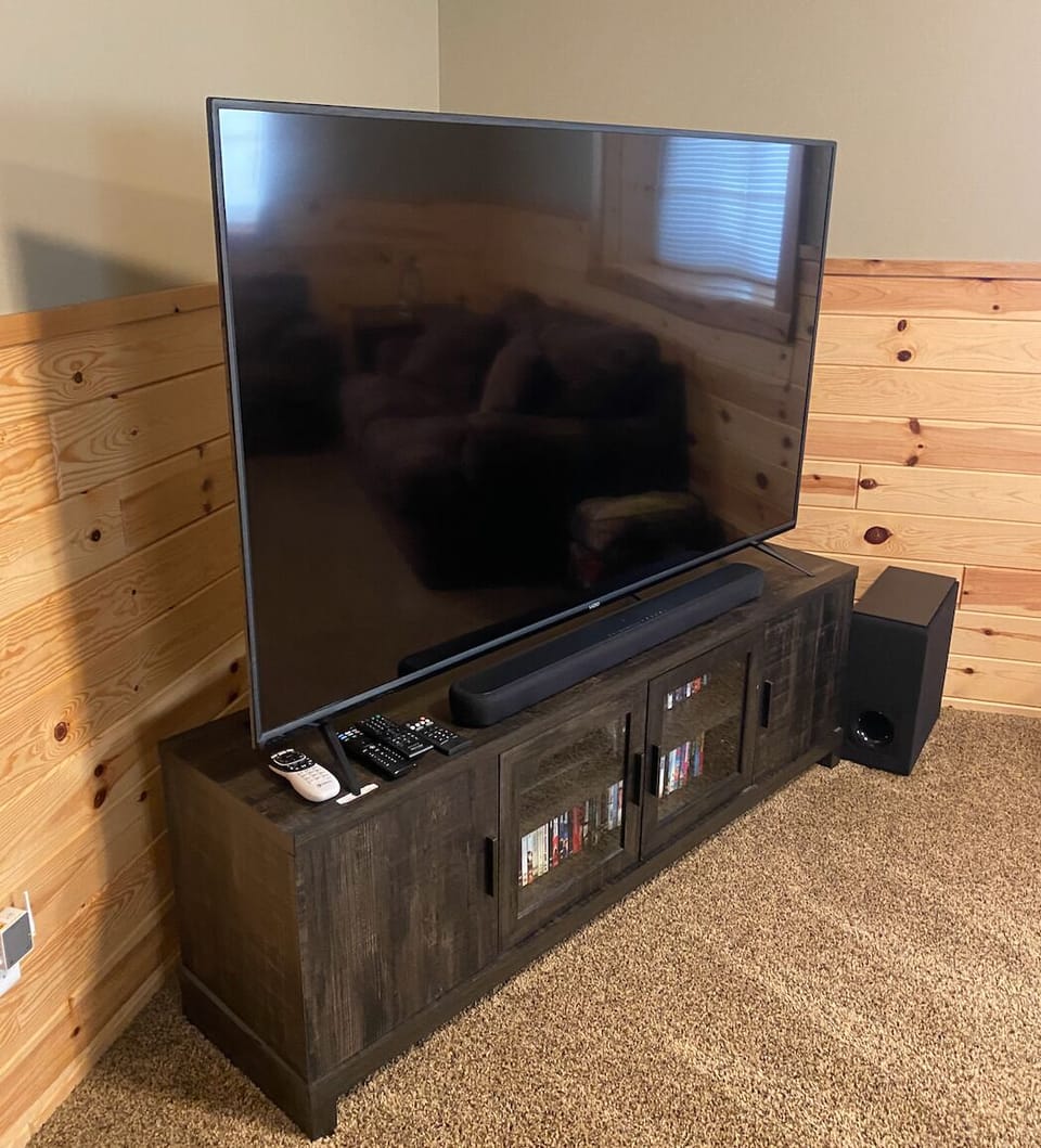 Large tv in the basement has cable, sound bar, and dvd player. 