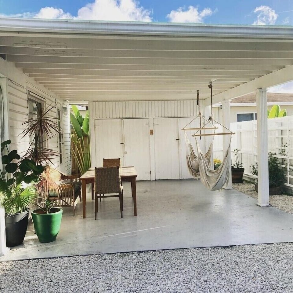 Outdoor space has a dining table, hanging hammock chairs and Bimini ring toss.
