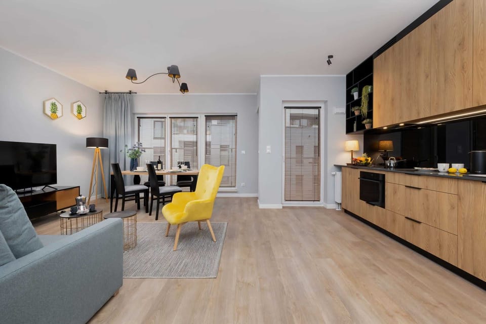 Open-concept living room with dining and kitchen area, wooden flooring, and stylish furniture.