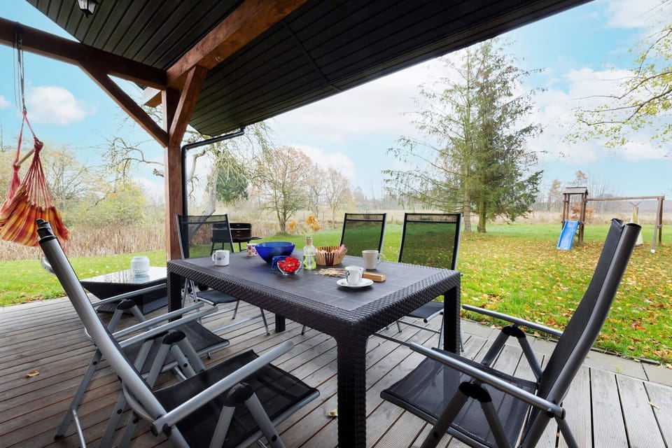 A terrace with a table, chairs, and a view of a garden, ideal for al fresco dining or relaxing outdoors.