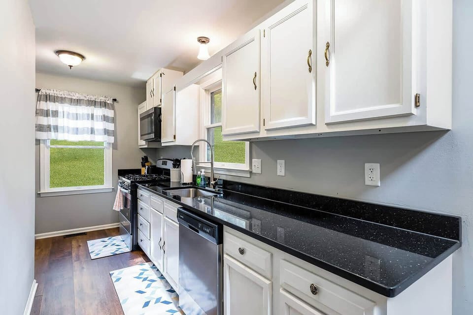 Fully-stocked kitchen with granite counter, dishwasher, stove/oven, and microwave.