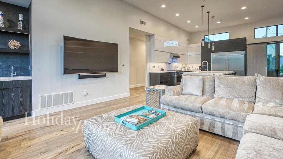 Spacious living room with high ceiling, modern décor & seamless kitchen flow.
