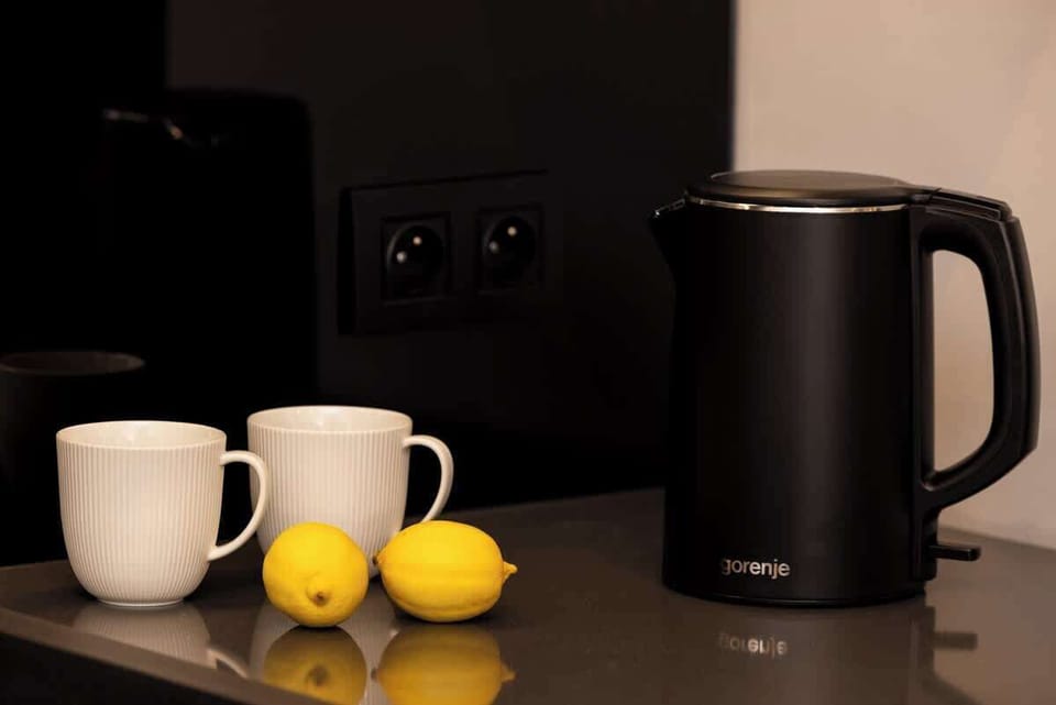 A counter with a kettle, mugs, and lemons placed next to a modern power outlet for easy access.