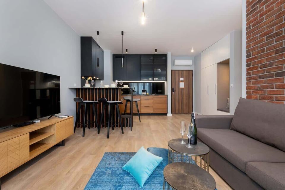 Open-concept living room with dining and kitchen area, wooden flooring, and stylish furniture.