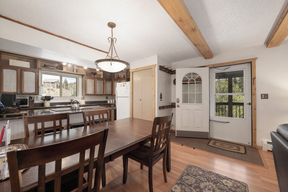 Step into your welcoming open-concept space where rustic wood beams frame a fully-equipped kitchen and dining area perfect for gathering.